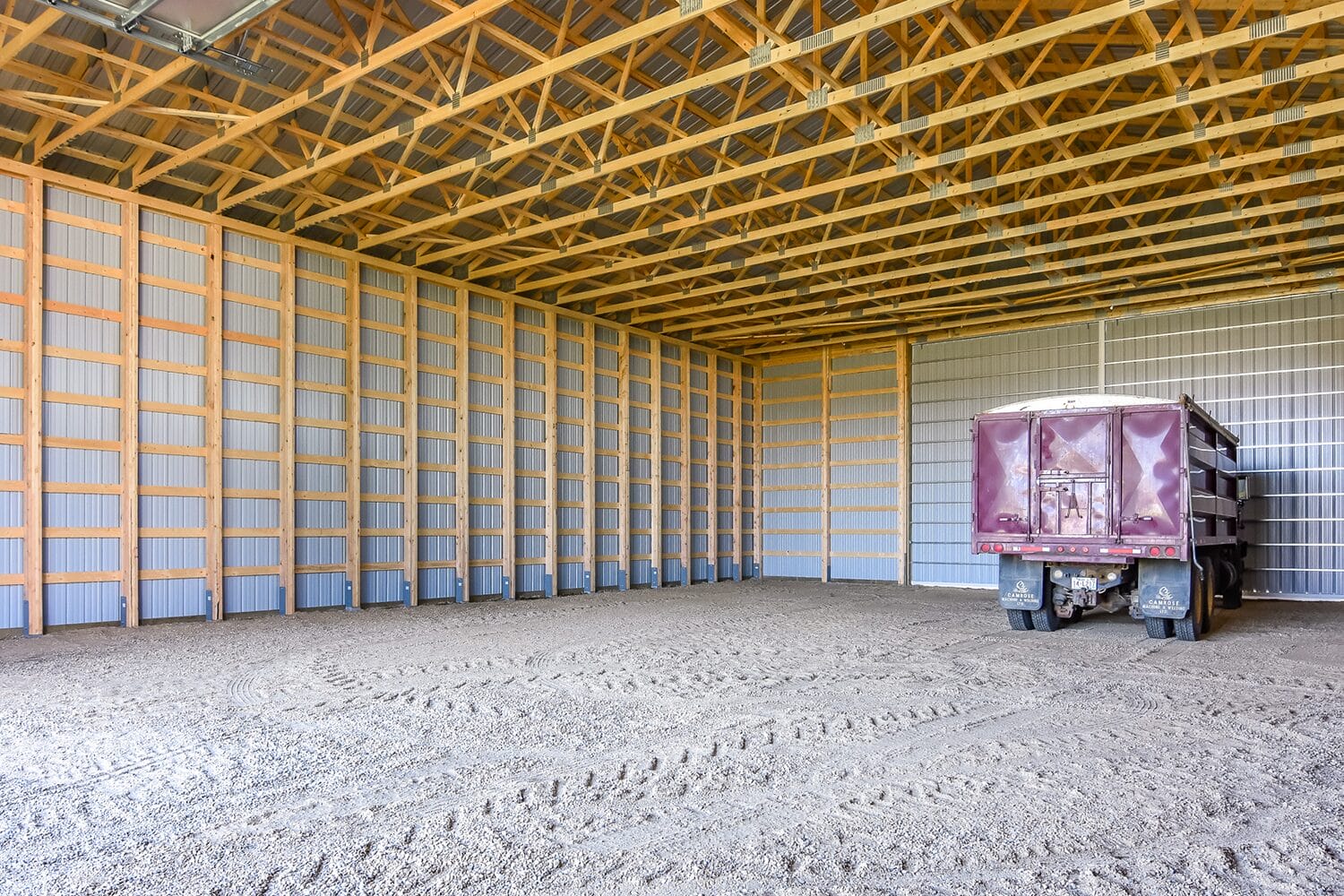 A lone truck sits inside a post frame building