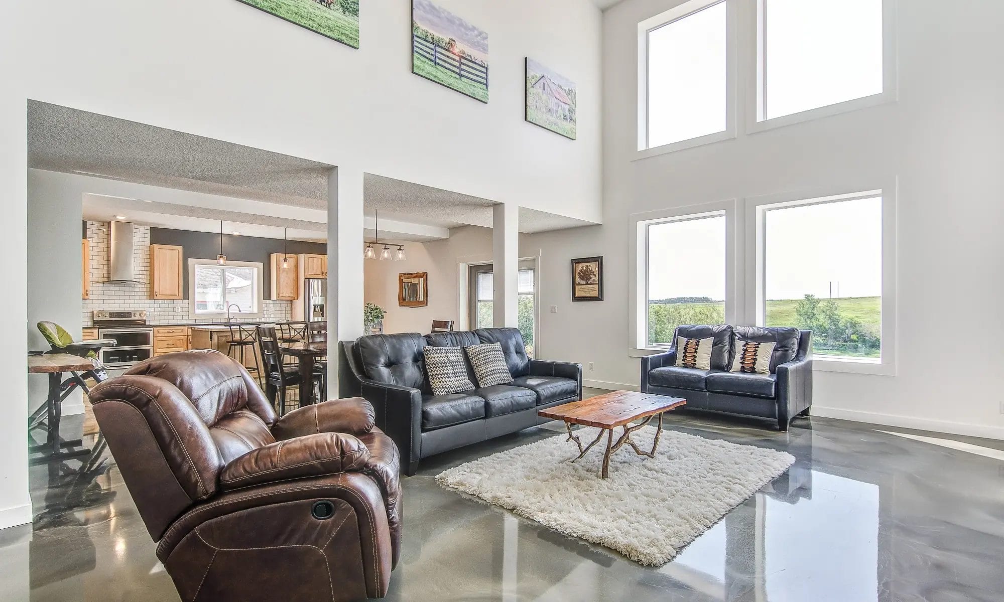 Bright and modern barndominium interior with open concept layout, large windows, and polished concrete floors.
