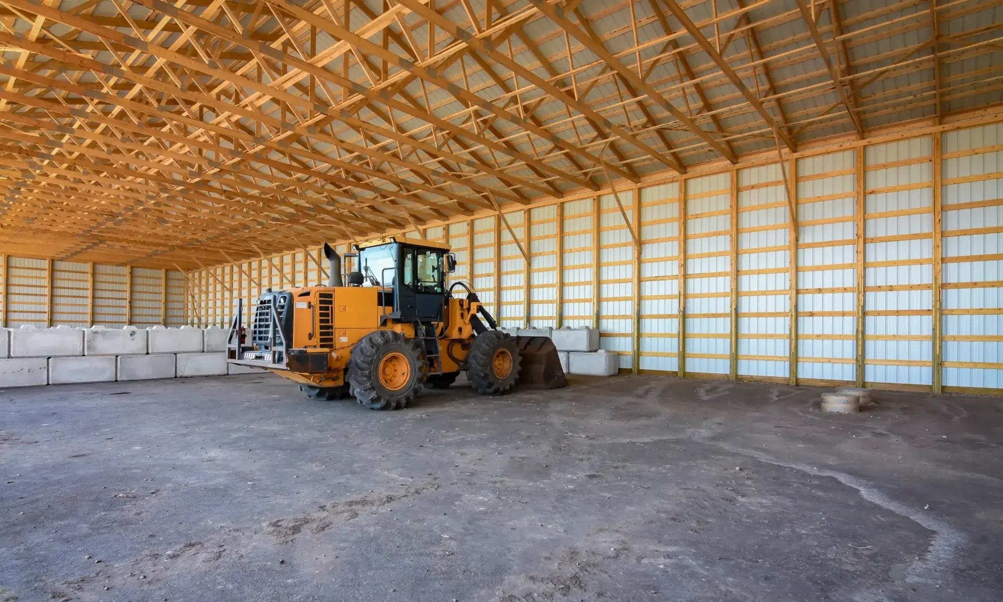 Heavy equipment sits inside a post frame commercial building