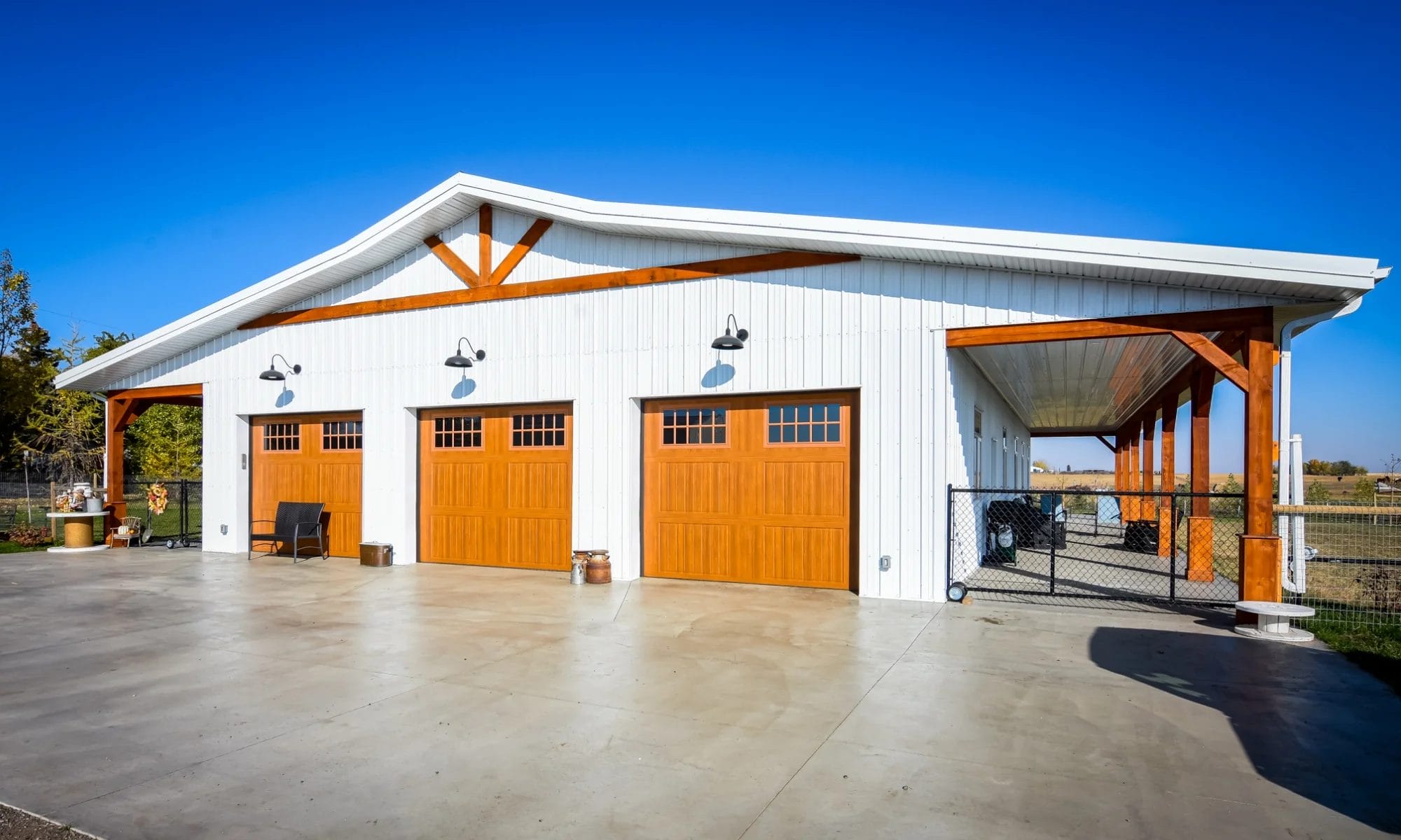 White barndominium shop home with wood-tone garage doors and spacious shop area.