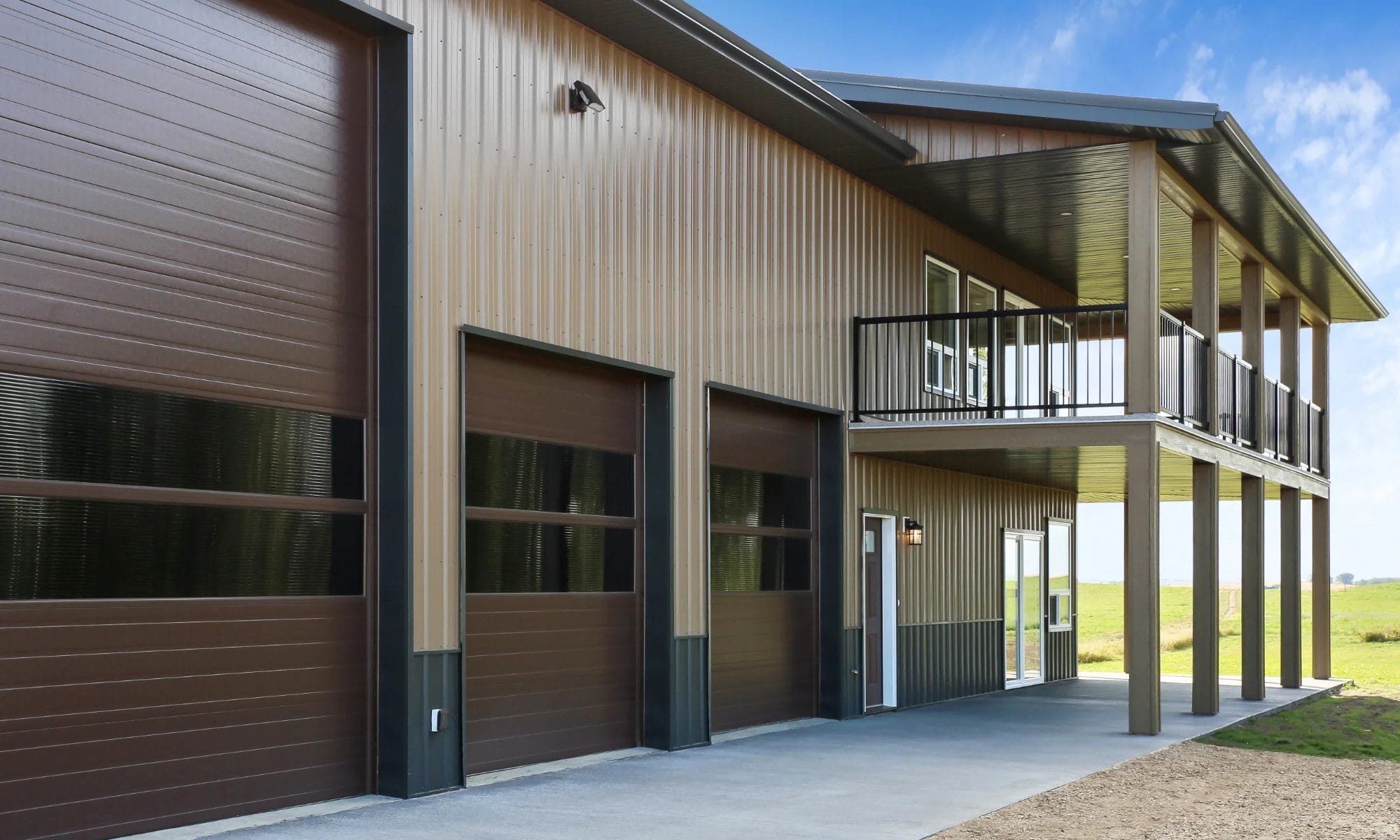 Two-Storey barndominium shop home with upper balcony, modern metal siding, and integrated garage doors.