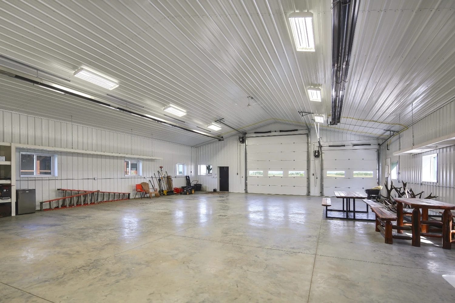 A monitor-style shop has a vaulted ceiling inside. The building is finished with insulation, metal cladding, and a concrete floor.