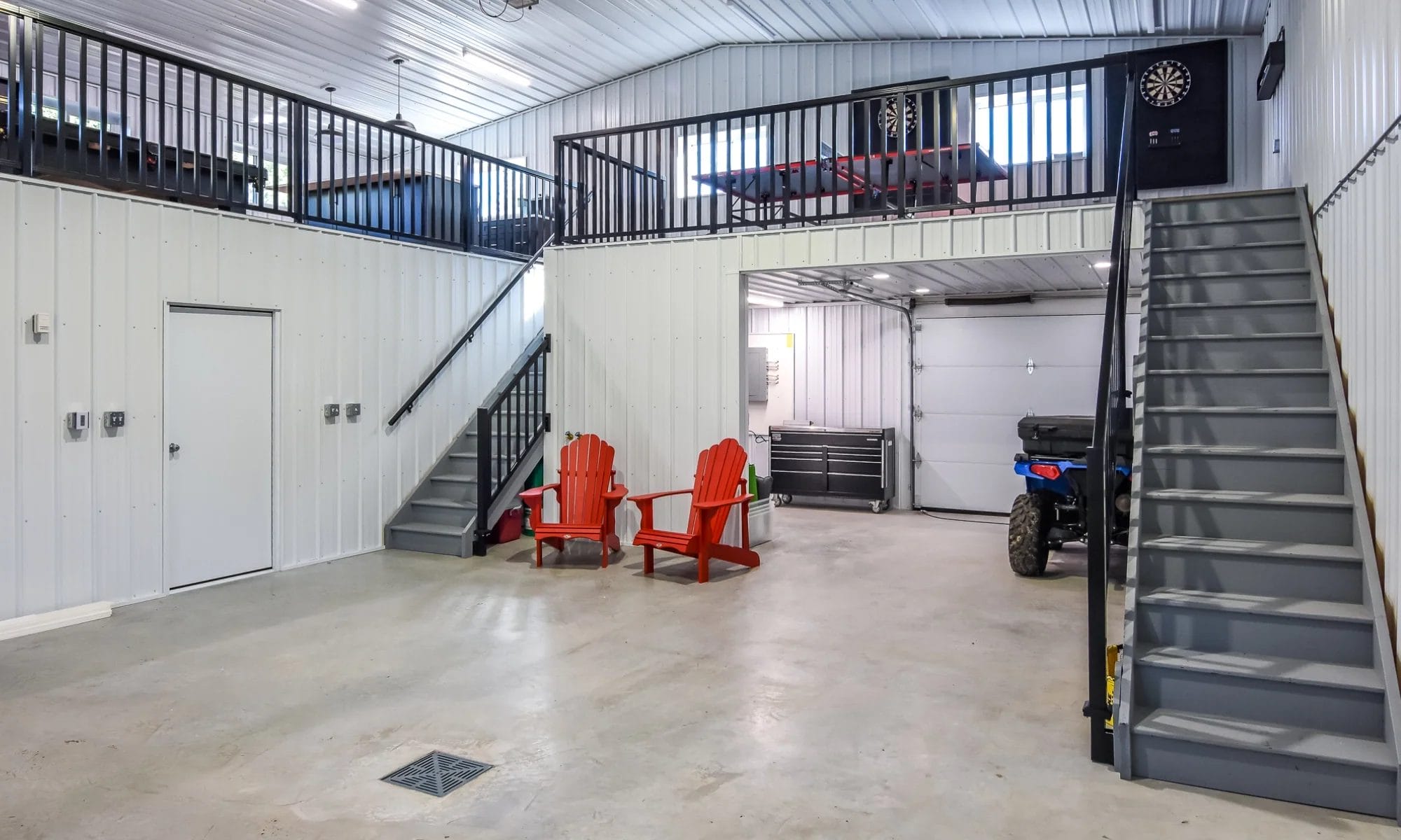 Interior of a custom acreage pole barn building featuring lofted recreational space, garage space, and fully finished interior with metal cladding and insulation.
