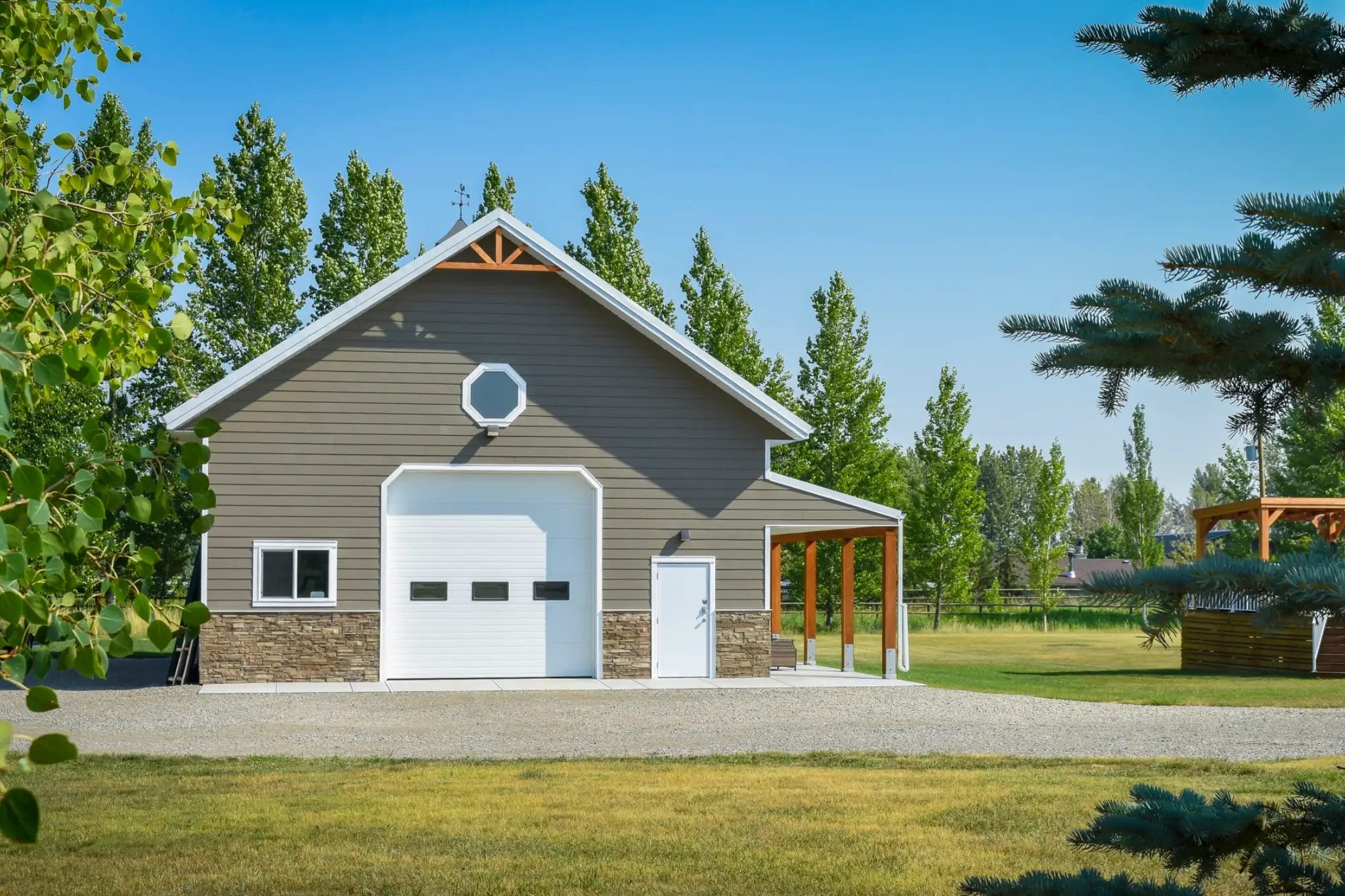 Stone and wood accents on a post frame garage elevate the appearance on an acreage estate property.
