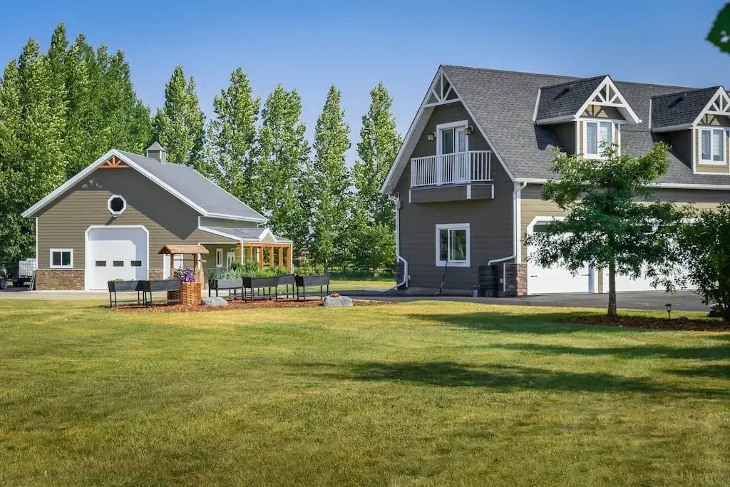 Detached post frame garage sits next to a house on an upscale acreage property