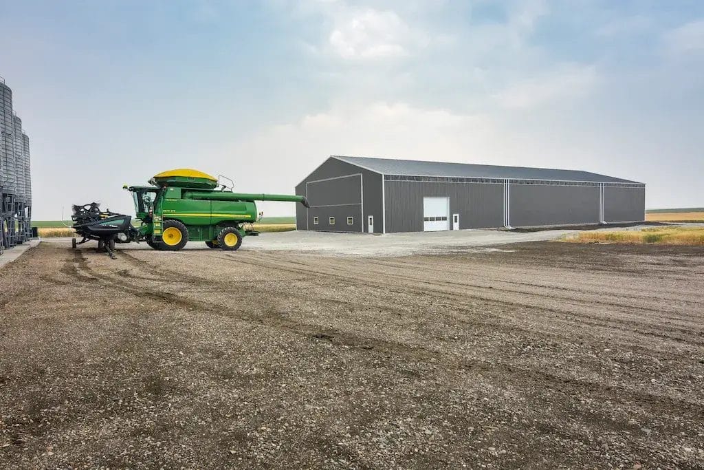 John Deere combine parked outside an 80' x 200' machine shed