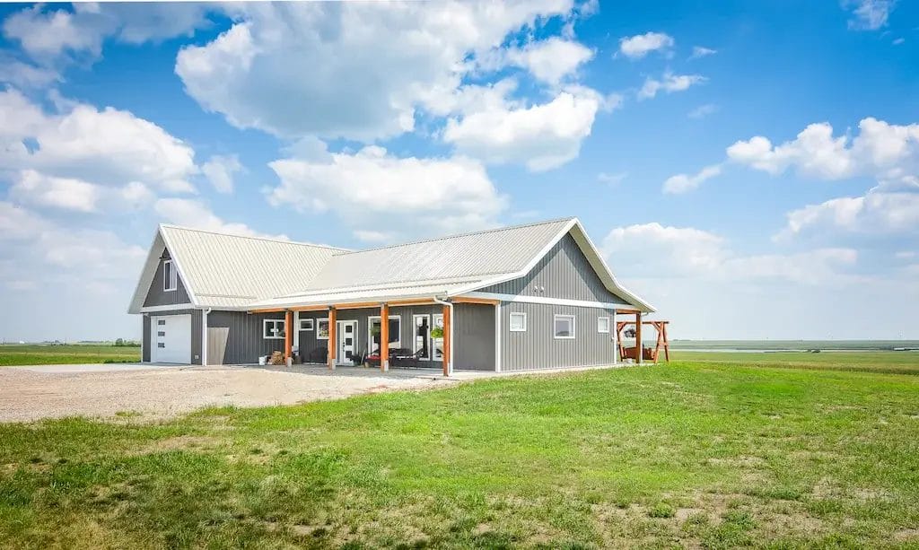 The front porch of a 4 bedroom barndominium with loft above the garage features exposed posts and beams for a rustic appearance