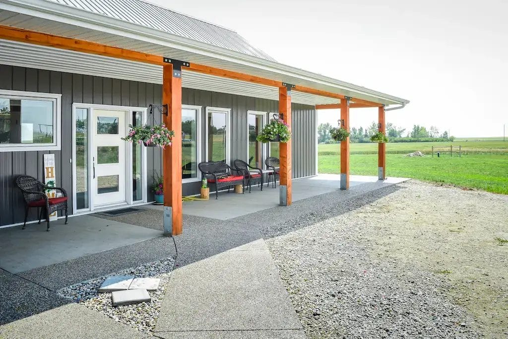 Front entrance to 4 bedroom barndominium features covered front porch with exposed posts and beams