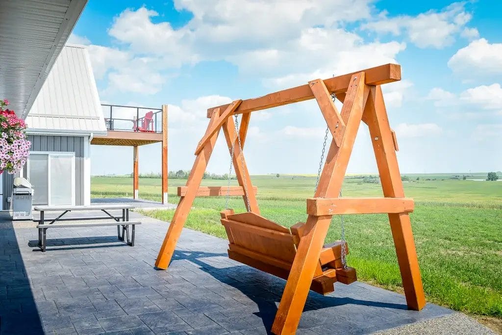 Porch swing on the back deck of a barndominium faces out over the surrounding countryside