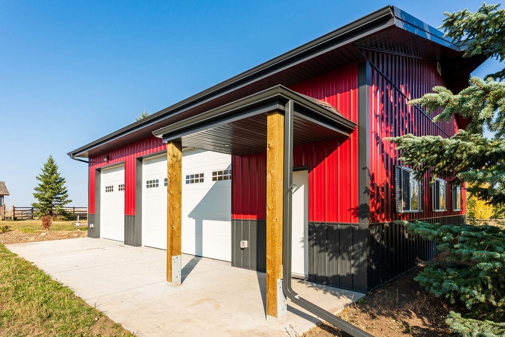On a red and black acreage outbuilding, eavestrough and downspouts direct runoff away from the foundation
