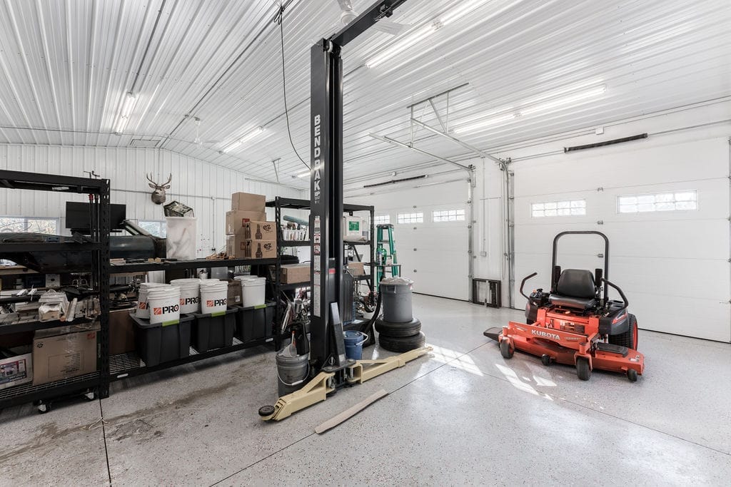 Interior of a post frame acreage outbuilding accommodates a car lift, and provides ample room for storage and working on cars