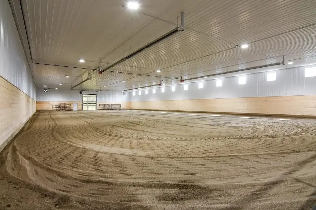 Post frame riding arena interior with groomed footing