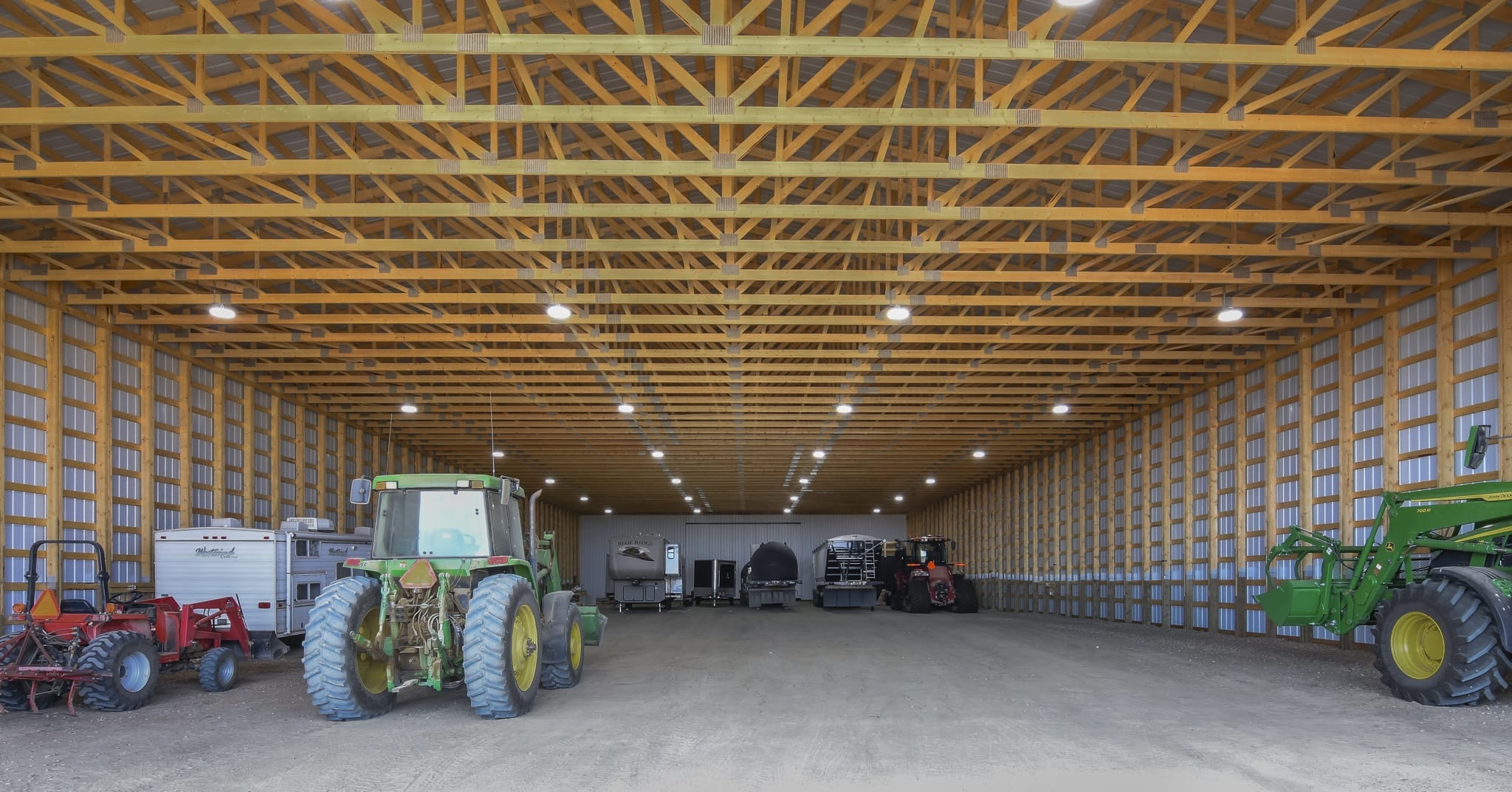 The unfished interior of a machine shed. filled with tractors and other farm equipment.