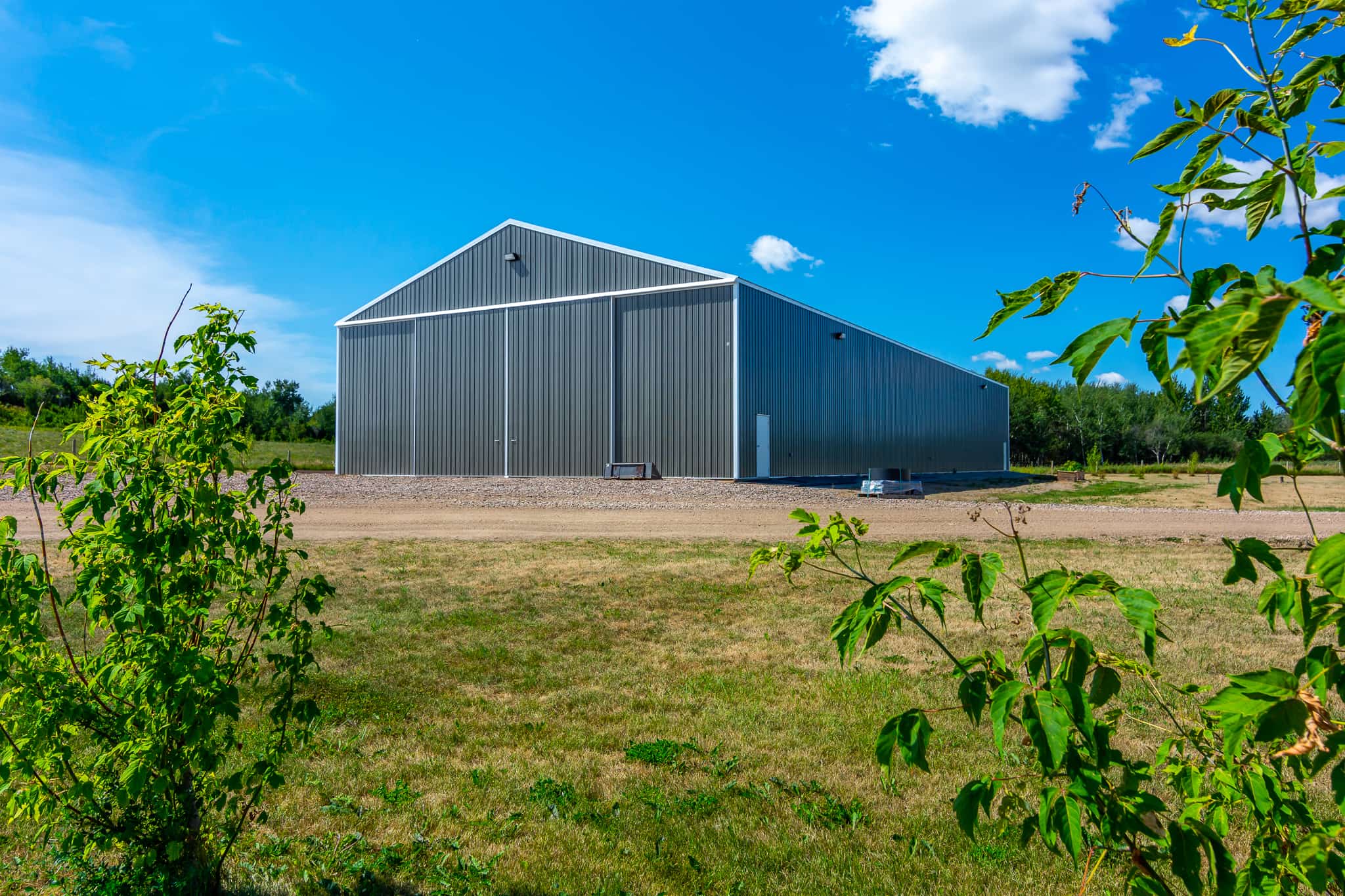 Viewed from afar, this post frame cold storage building for farm equipment, protecting it from damaging weather.