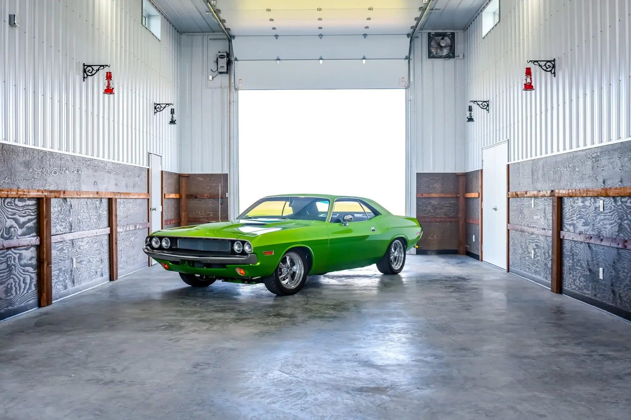 A classic green sportscar sits inside the fully finished interior of a post frame monitor-style hobby shop