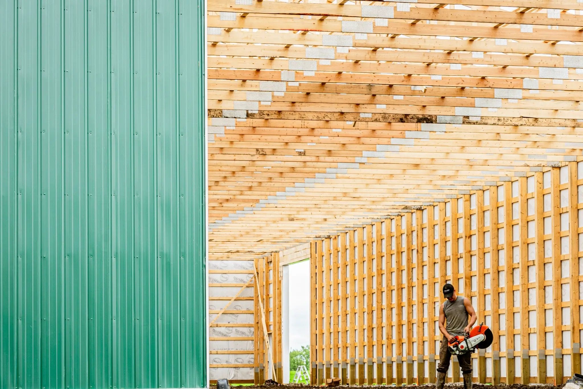 A Remuda Building crew member working on the construction of a modern post frame riding arena.