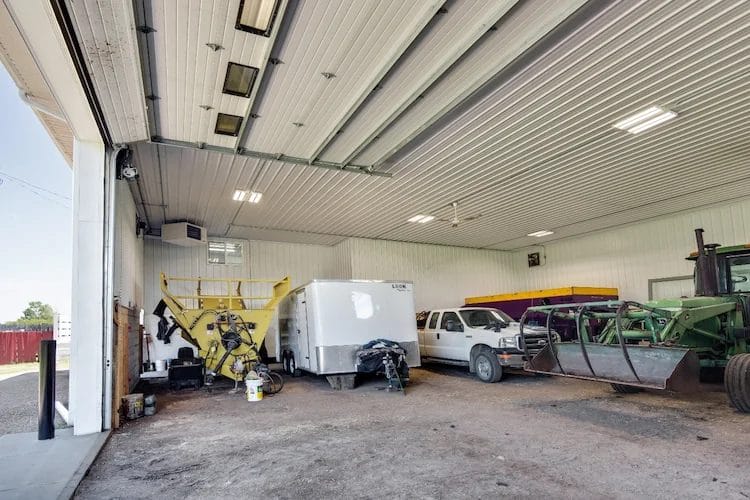 Trailers, trucks, tractors, and other equipment stored inside a calving barn.