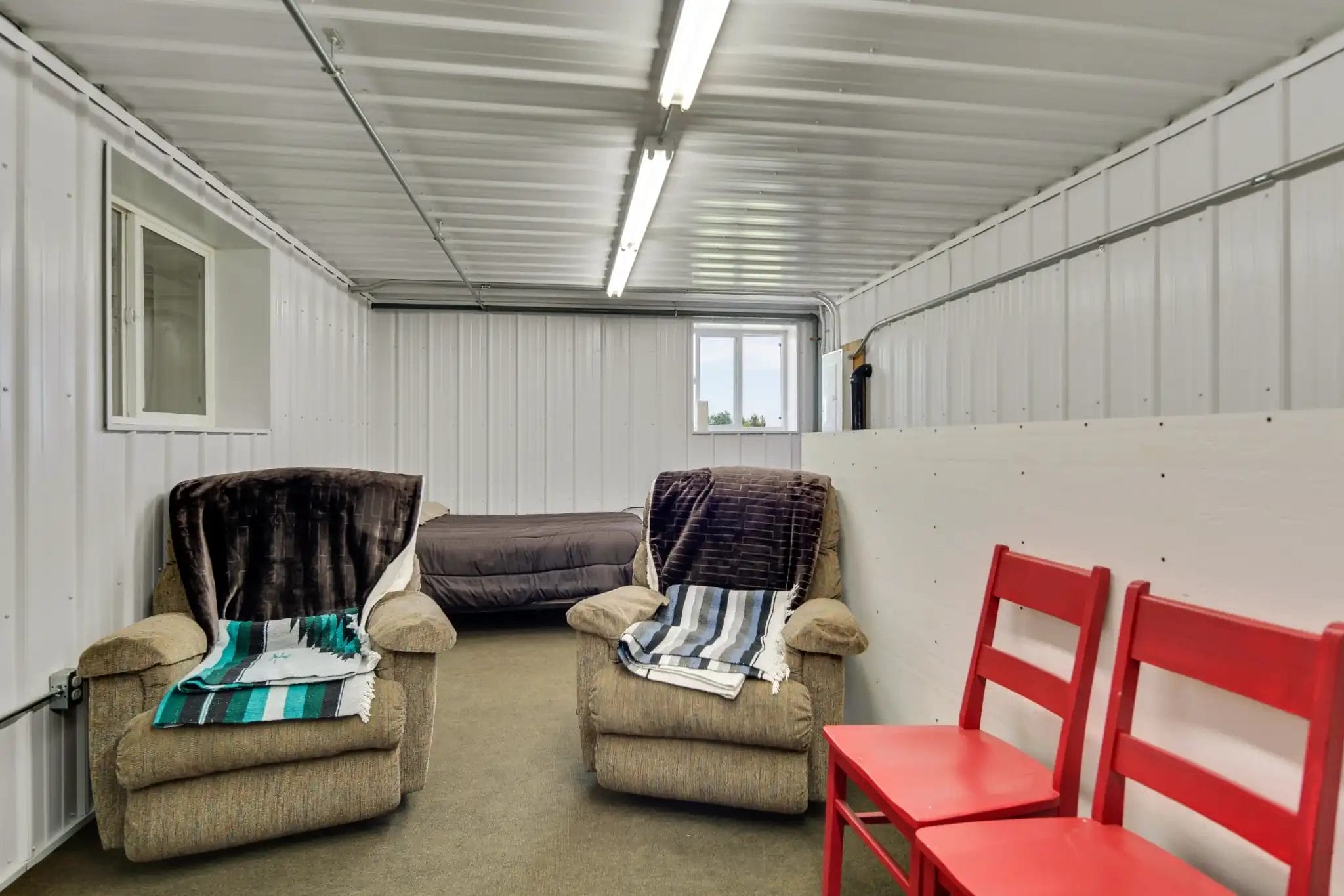 A second-floor living quarters inside a calving barn with bed and chairs.