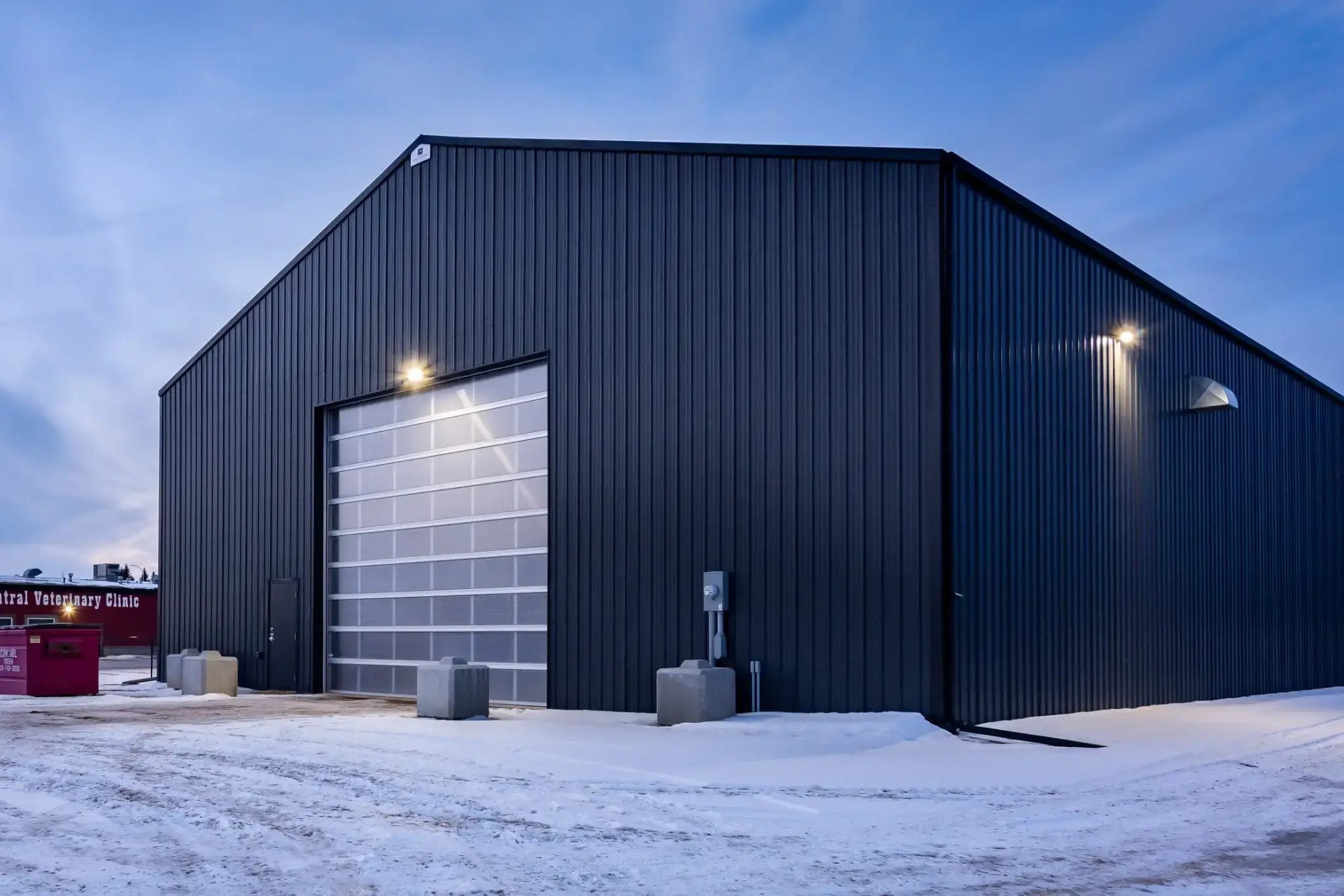 Agricultural building during dusk with exterior lights shining.