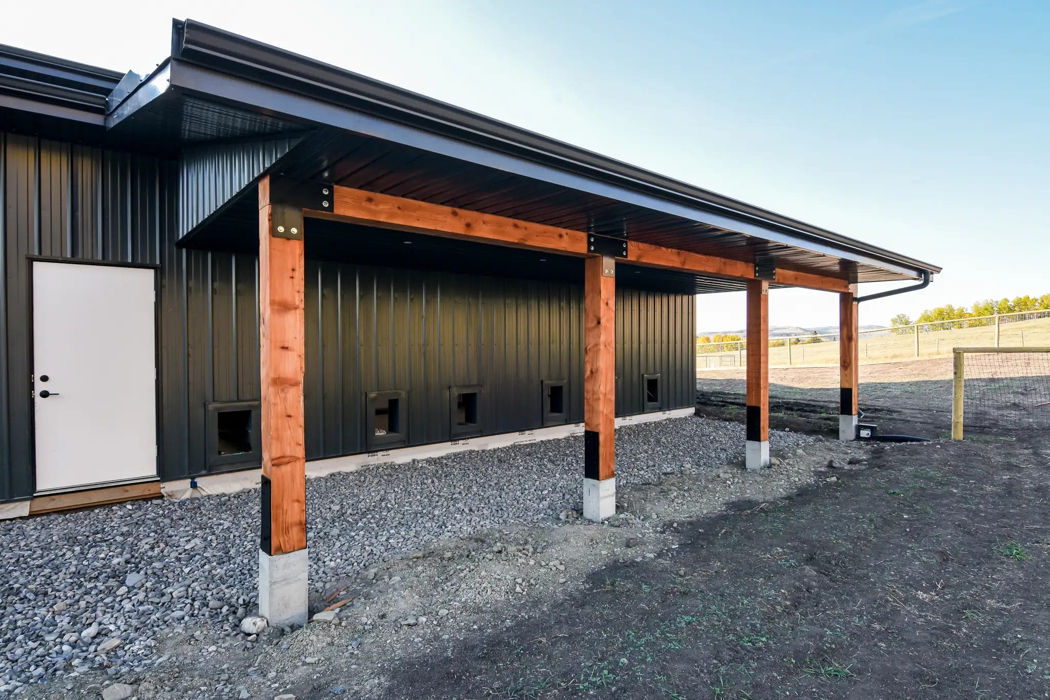 Small open lean-to at the rear of a one story barndominium.