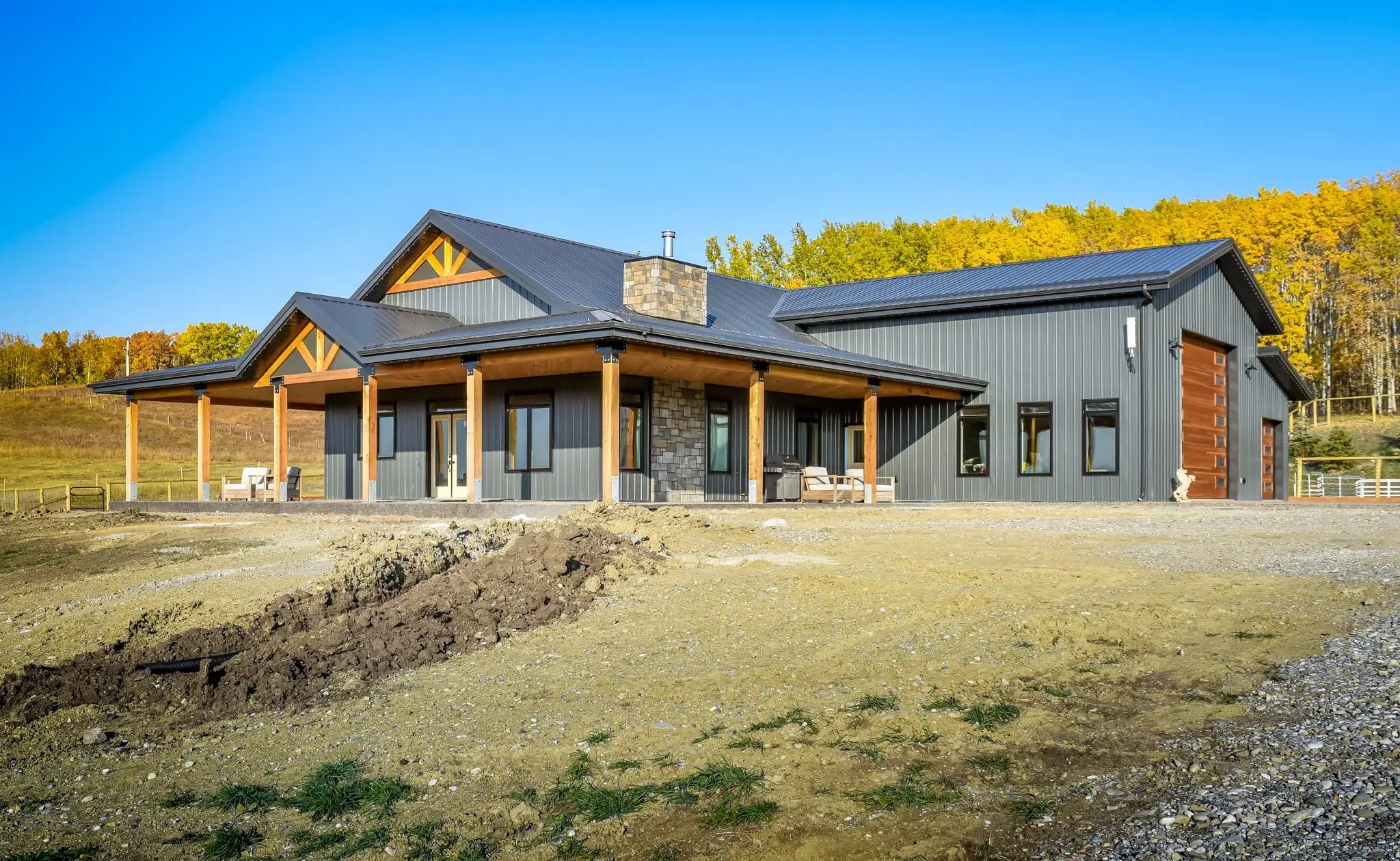 Barndominium with a warp around porch sitting distinctively against the country backdrop.