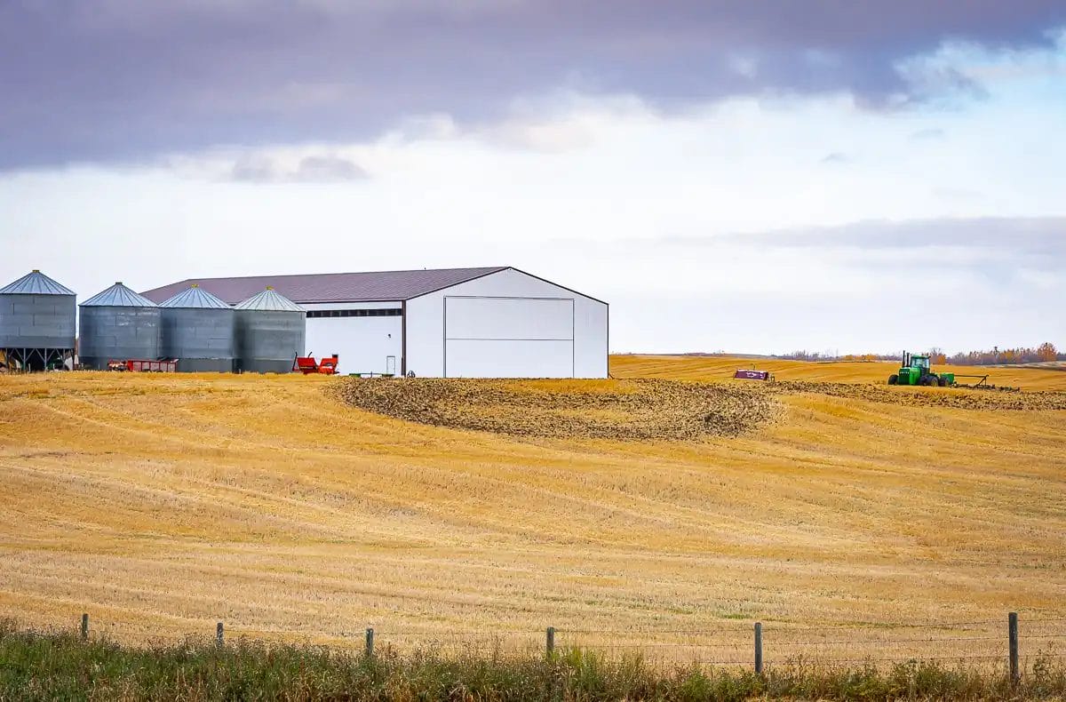 A large farm post frame building on a cloudy day in a field
