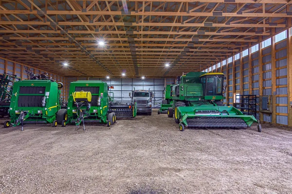 Farm machinery and trucks sitting inside a post frame machine shed for cold storage
