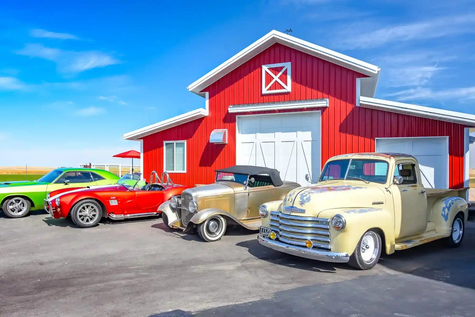 A Post Frame Acreage Building With Classic Cars Parked In Front