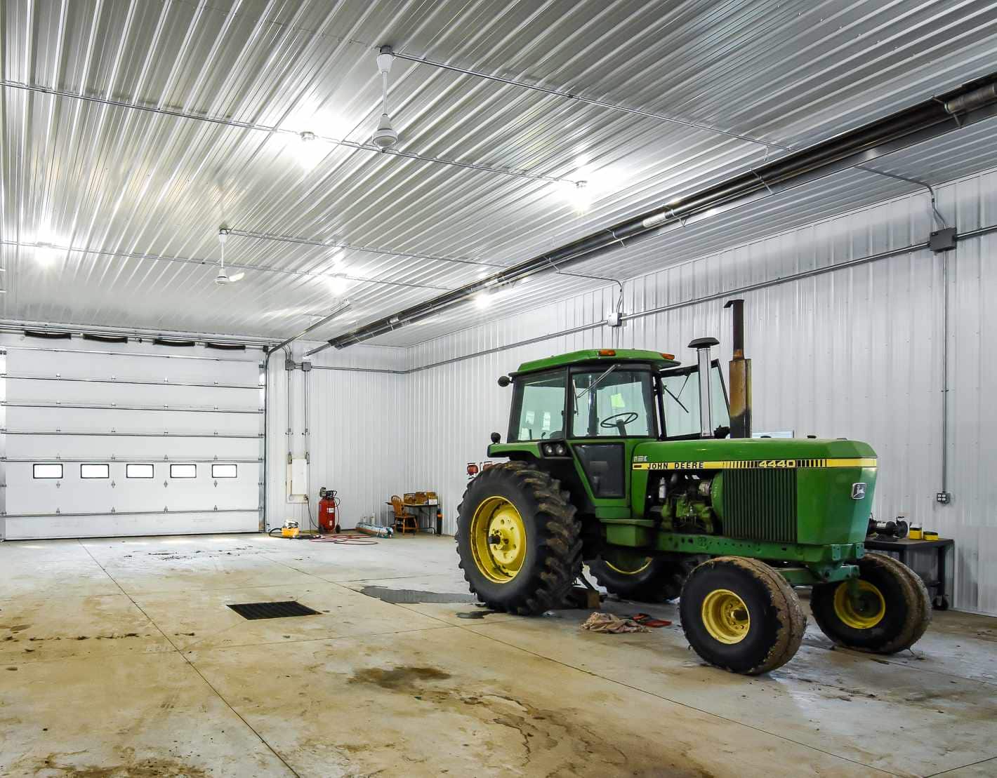 Hard working insulated farm shop interior finished with metal and heat. A tractor is being worked on inside
